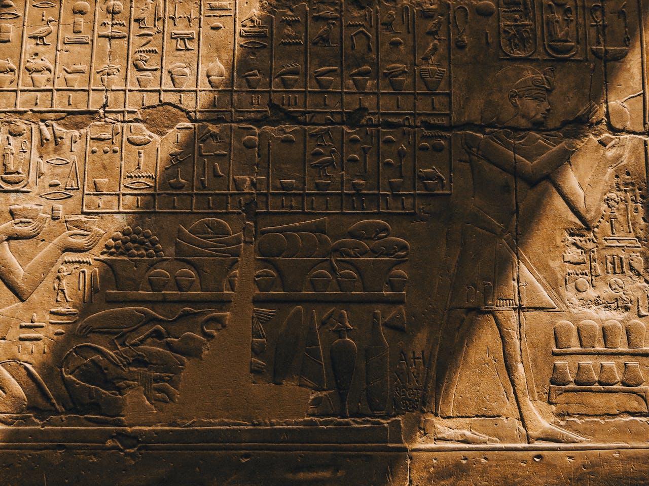 services-img Detailed view of ancient Egyptian hieroglyphic carvings on a stone wall with warm lighting.