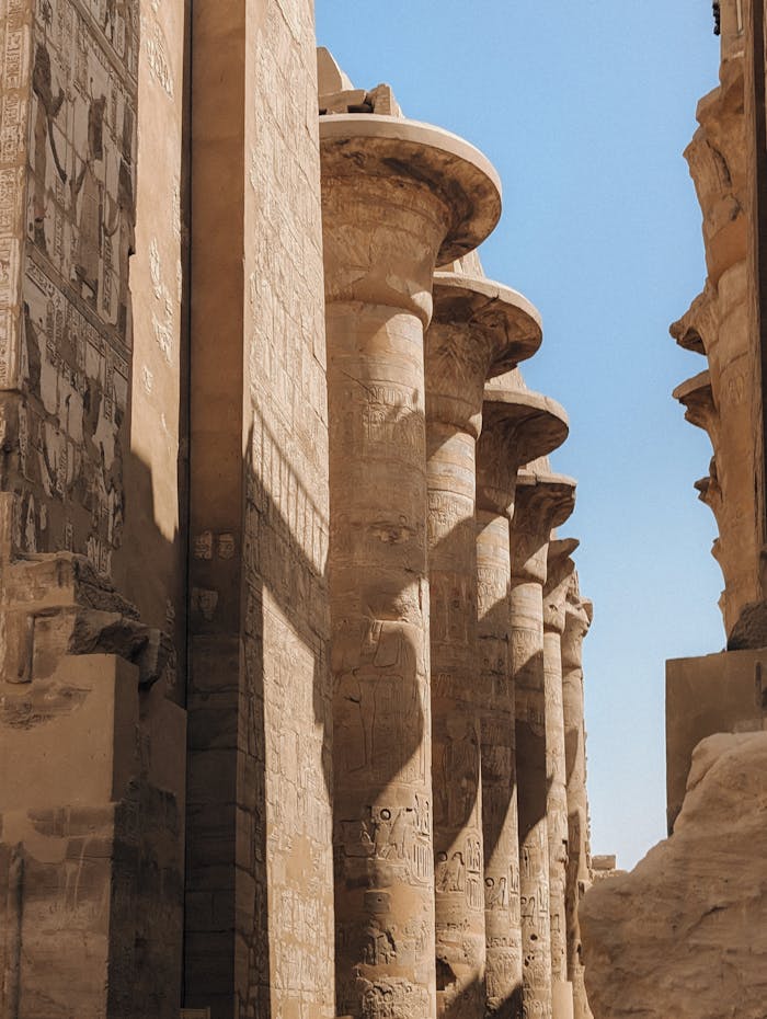 Explore the ancient grandeur of Luxor's Karnak Temple with stunning columns under a clear blue sky.
