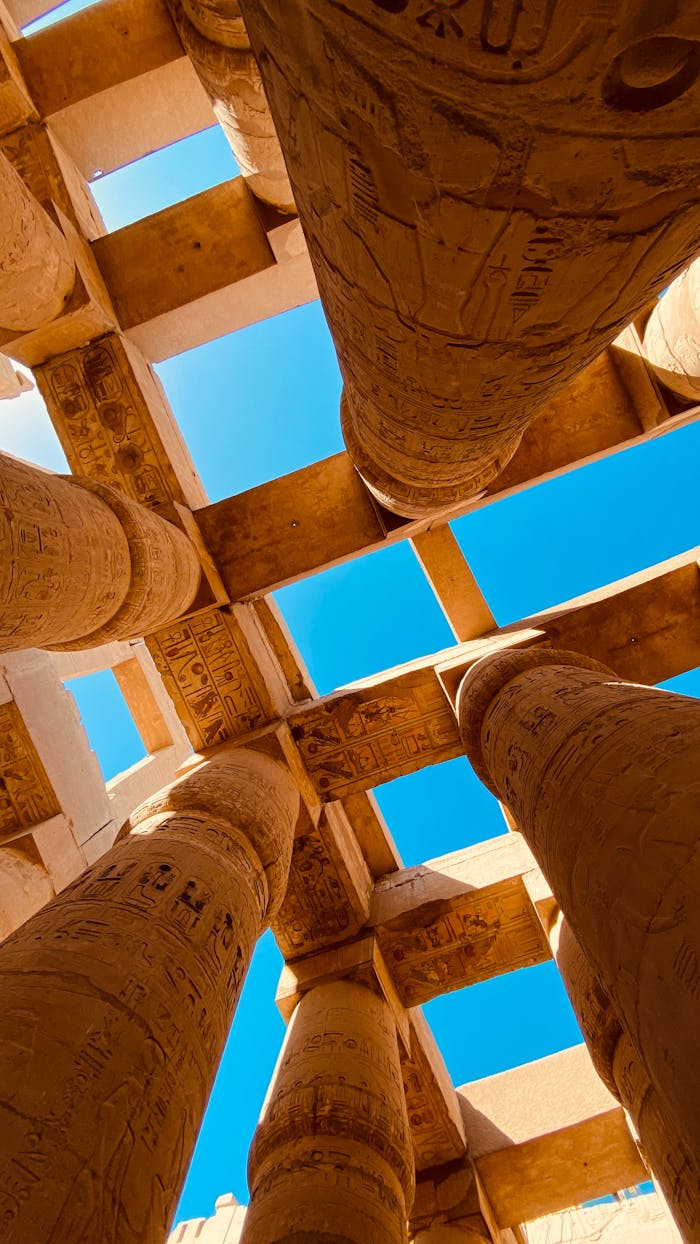 An upward view of the ancient hieroglyph-covered pillars at the Karnak Temple in Luxor, Egypt.